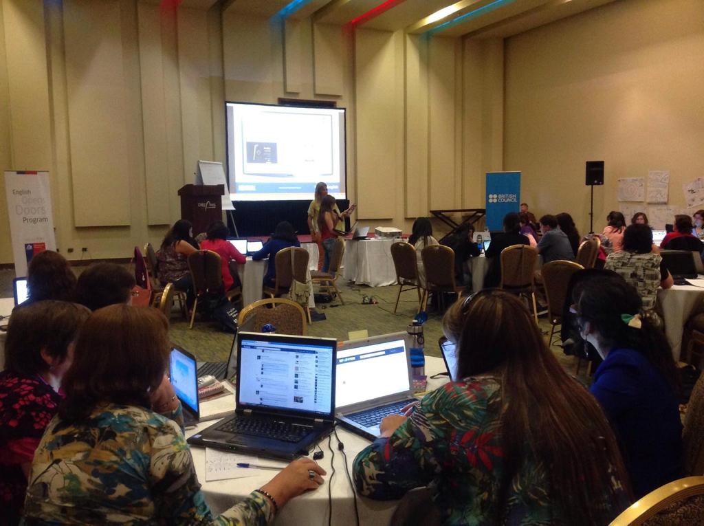 Teachers at laptops attending an in-person training session with British Council and English Opens Doors Program banners